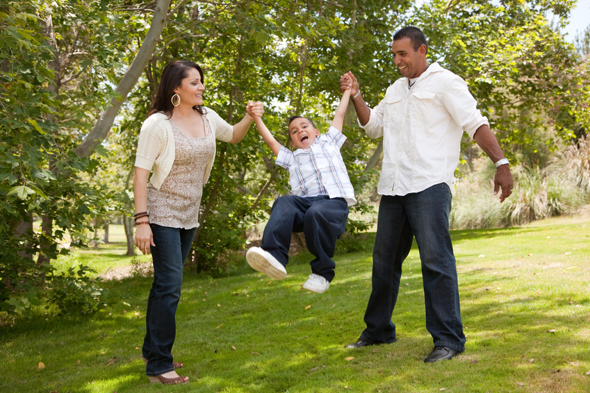 child swinging in arms of parents